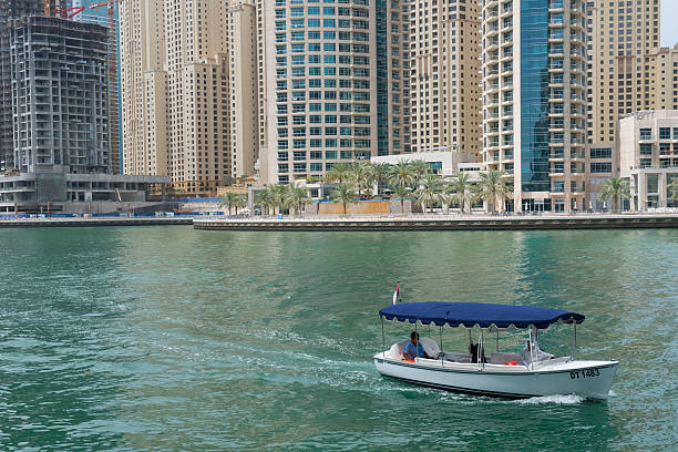 Dubai, UAE - March 27, 2015: Apartment skyscrapers surrounding Dubai Marina. Taxi passenger boat close up