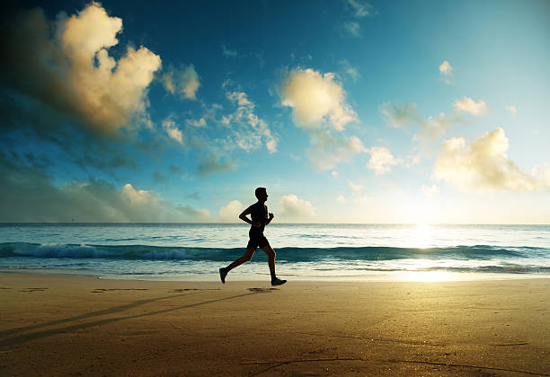 istock Man running on tropical beach at sunset 636813748