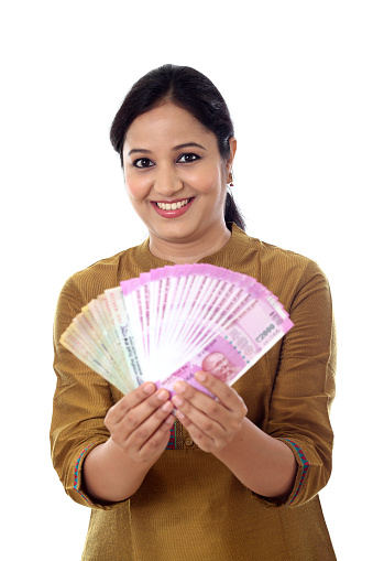 Young woman holding Indian 2000 rupee notes against white background