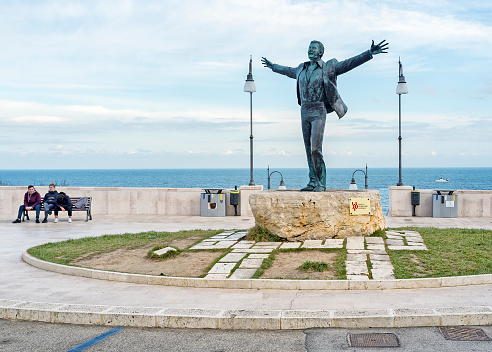 Polignano a Mare, Italy - December 20, 2016: Statue of Domenico Modugno, (by the sculptor Hermann Mejer), a famous entertainer known for the song, Nel Blu Dipinto di Blu, universally known as \