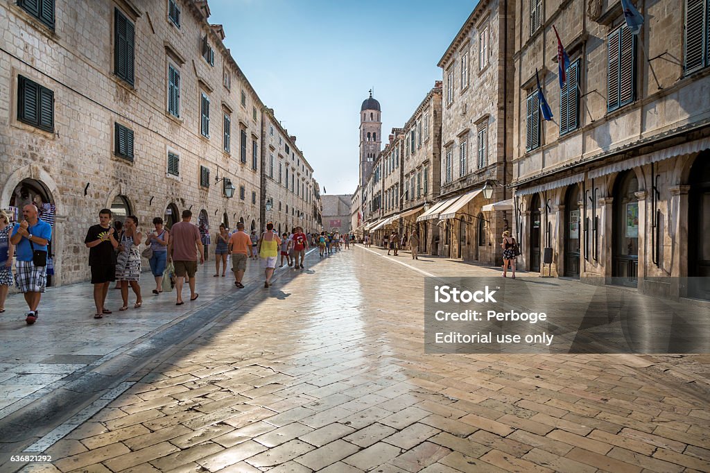 Shiny marble like street in central Dubrovnik. Dubrovnik, Croatia - July 18, 2015: Shiny marble like street in Dubrovnik with people passing by. Perspective view.  Adriatic Sea Stock Photo