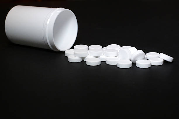 istock White pills, medicines, on a blach background 636827704