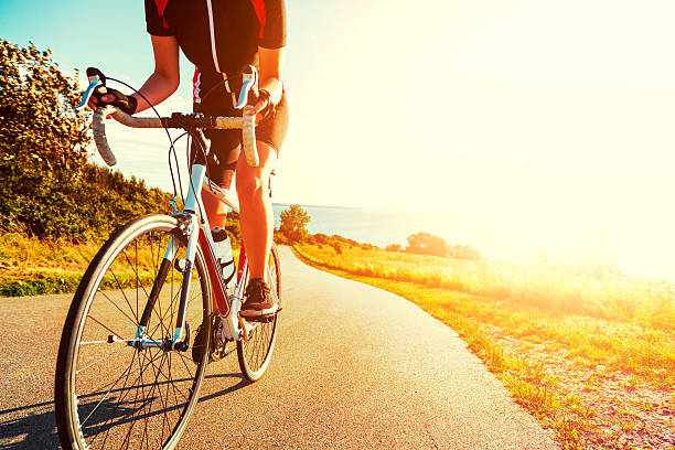 istock Professional athlete rides bicycle up a hill at sunset 636828120