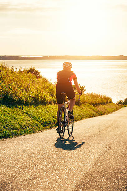 istock Cyclist rides bike downhill while sun sets 636828998