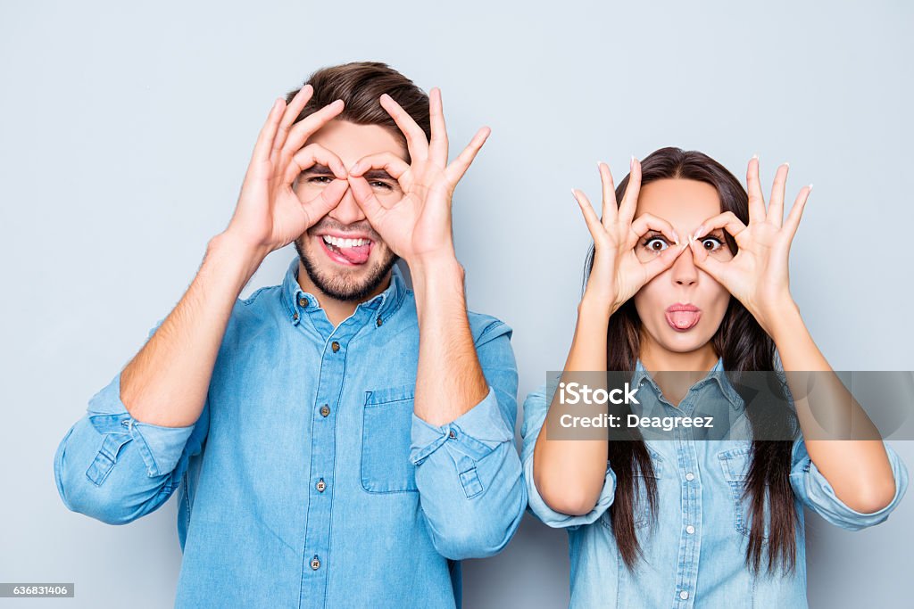 happy couple making glasses with fingers and showing tongue Cheerful happy man and woman making glasses with fingers and showing tongue Backgrounds Stock Photo