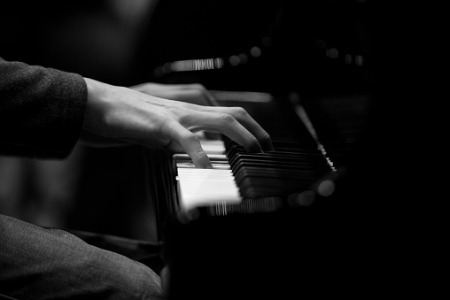 Hands musician playing the piano closeup in black and white