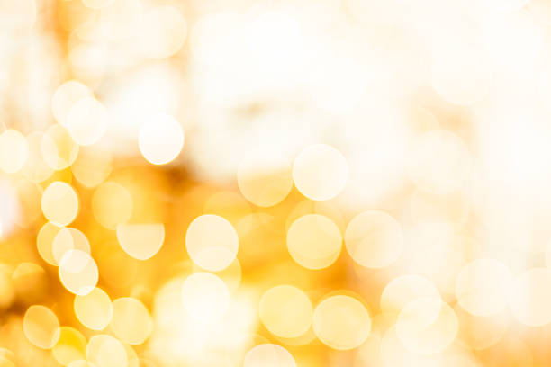 Defocused and toned high key circular white and gold light pattern. Actual camera effect with slight visible lens imperfections.