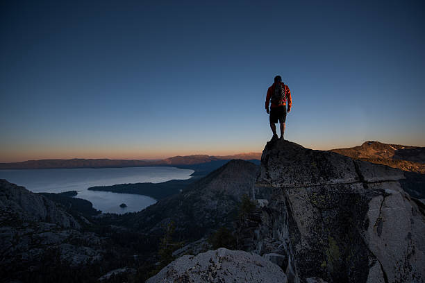 uomo in cima a una bellissima cima di montagna nel lago tahoe - conquering adversity mountain hiking mountain climbing foto e immagini stock