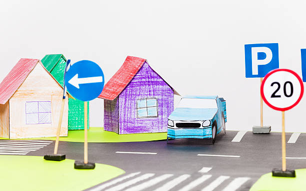 istock Paper car on a parking next to the houses models 636857976