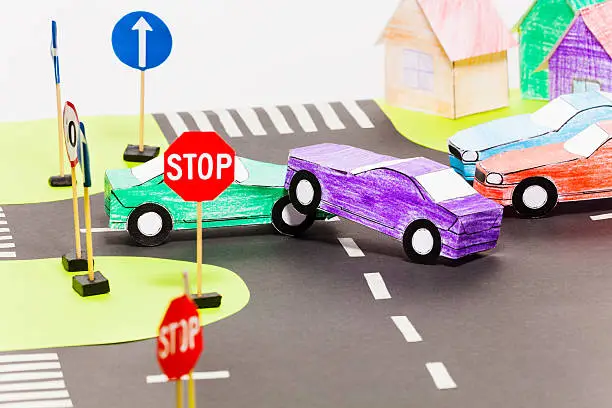 Road accident on a crossings with two handmade paper cars at the toy city