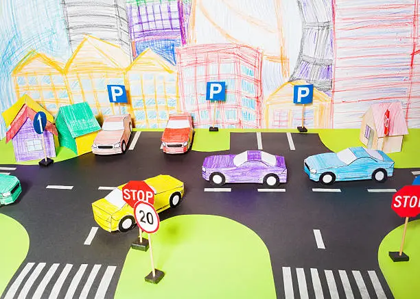The traffic on a roads handmade paper maquette in driving school with crossings, parking, road signs and toy cars