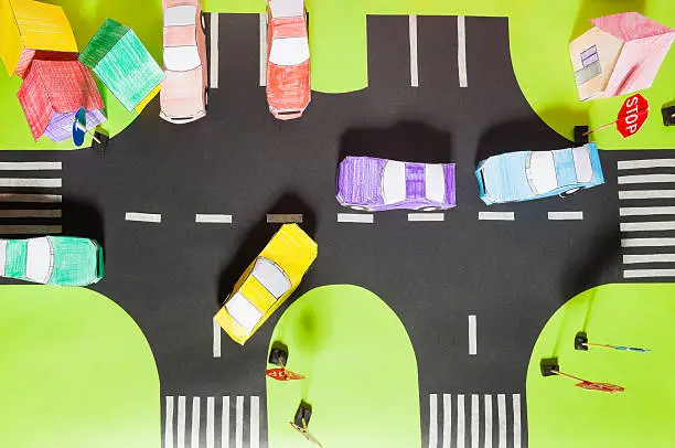 Top view of handmade road traffic with crosswalks, signs, parking and paper toy cars
