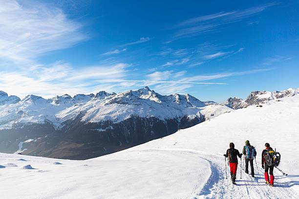excursionistas caminando por carretera cubierta de nieve en alta montaña - snow hiking fotografías e imágenes de stock