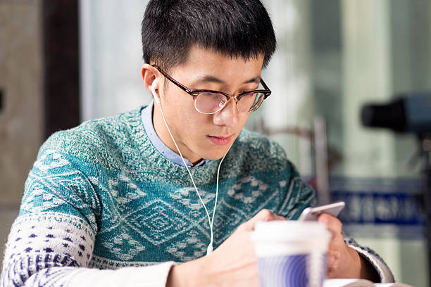 istock young asian man student with mobile phone in cafe 636861400
