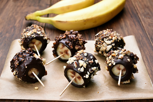 Frozen banana covered with chocolate and peanuts