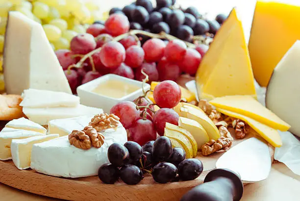 variation of selective cheese on wooden board with fruits