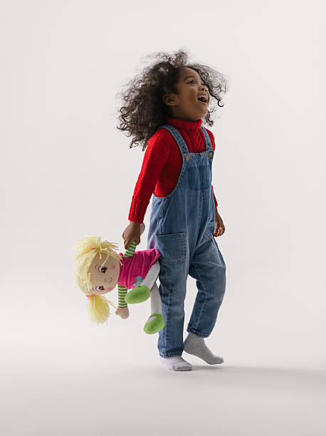 Cheerful african girl with toy African little girl holding her toy full length Portrait on plain background girl playing with doll stock pictures, royalty-free photos & images