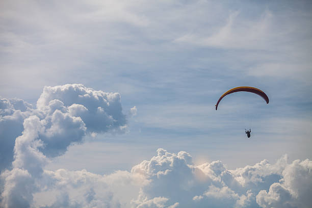 Para glider flying Color image of a paraglider flying, with clouds in the background. glider hang glider hanging sky stock pictures, royalty-free photos & images