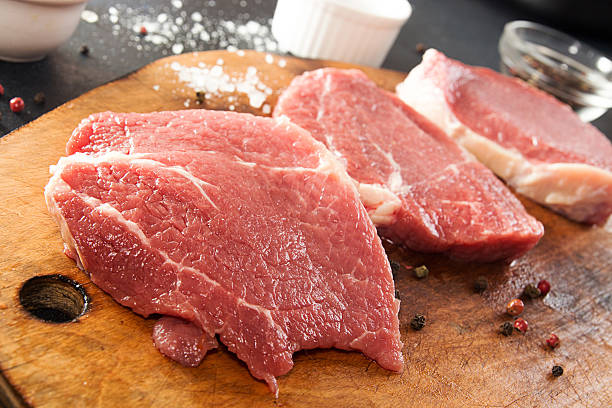 istock Cooking dinner. Overhead pieces raw pork steaks on chopping boar 636867772