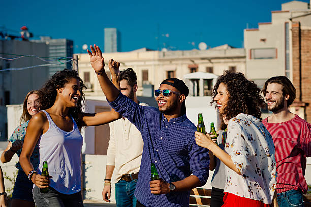 istock Happy friends dancing and drinking beer at rooftop party 636868960