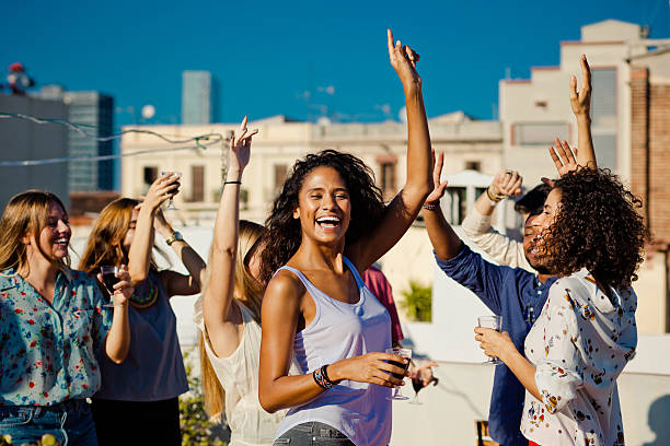 istock Happy friends dancing and drinking wine at rooftop party 636869684