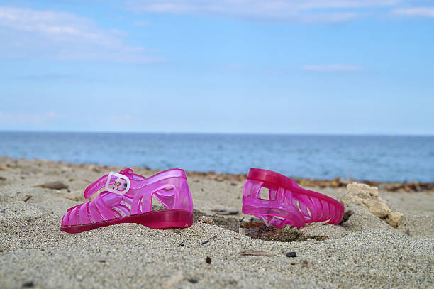 istock Pink children shoe on the beach.Selective focus 636874552