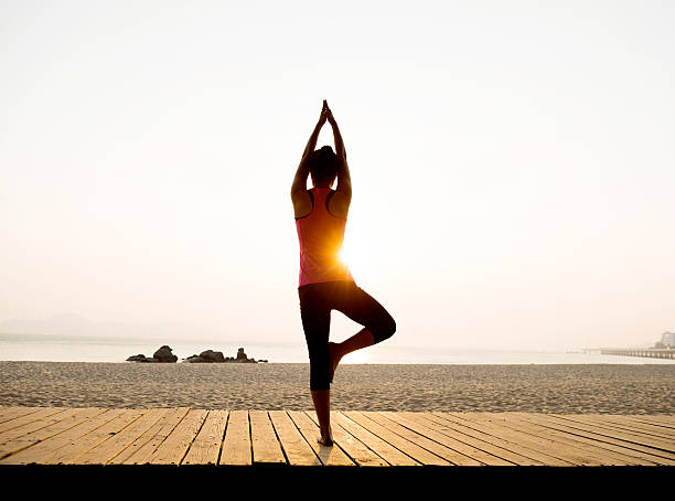 istock Woman in yoga pose at beach 636877156