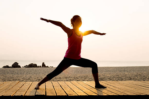 istock Woman practicing yoga at beach 636877450