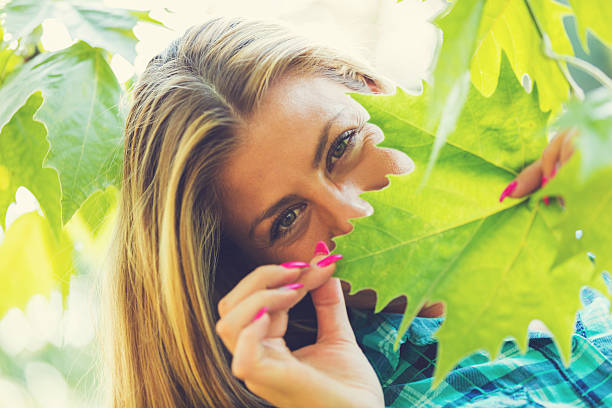 Girl hiding behind the leafs in the nature.