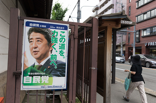 Kyoto, Japan - June 23, 2016 : A person walk past the street in Tokyo. Liberal Democratic Party of Japan poster with the Prime Minister of Japan, Shinzo Abe, at the street in Kyoto, Japan. 