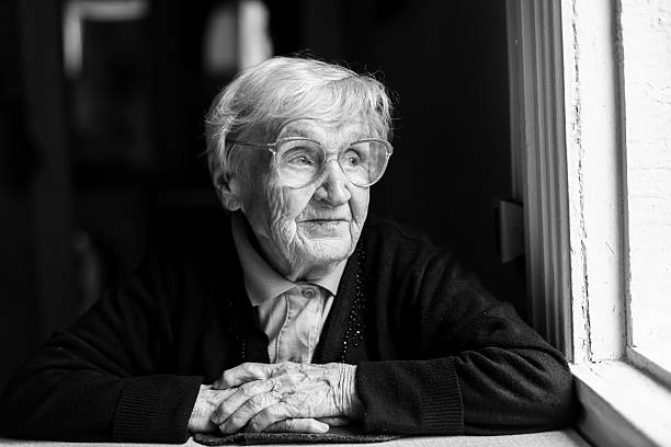 istock An elderly woman with glasses sitting at a table 636881500