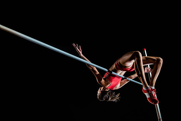 High jumper performing Young female high jumper clearing bar. athlete stock pictures, royalty-free photos & images