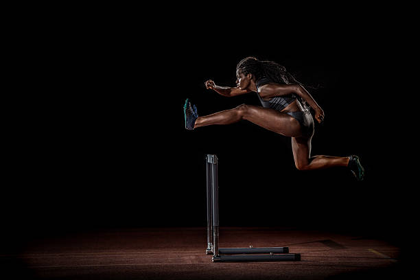 Athlete clearing hurdle Female athlete jumping over hurdle. hurdling track event stock pictures, royalty-free photos & images