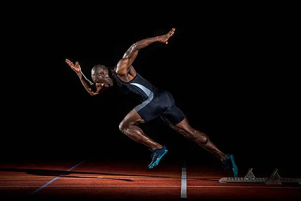 Young male athlete taking off from starting block.