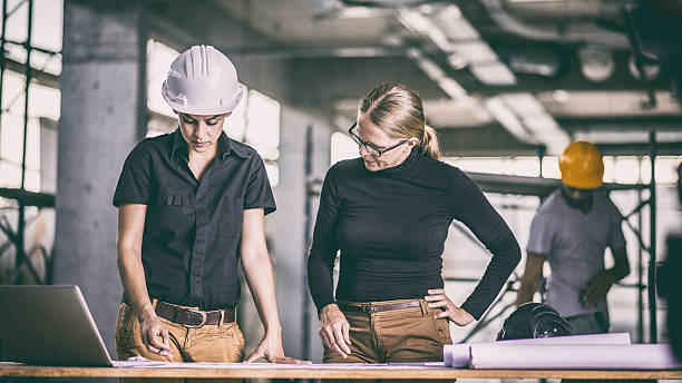 istock Female constructor and female architect reviewing blueprints 636889554