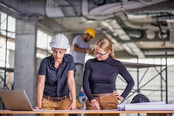 istock Female constructor and female architect reviewing blueprints 636889672