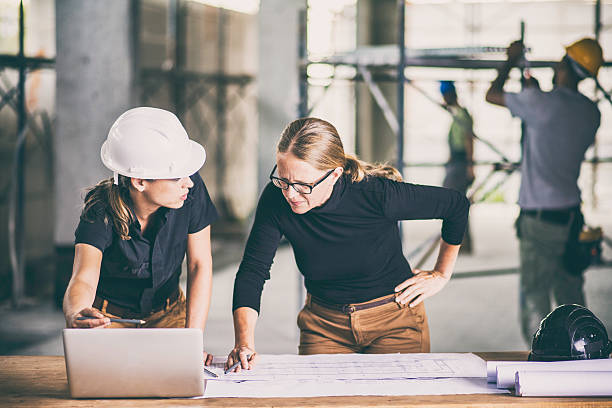 trabajadora de la construcción que consulta a un arquitecto - computer construction using laptop construction site fotografías e imágenes de stock