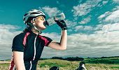 Professional female bike rider drinks water during break