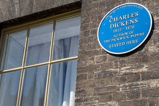 Bury St. Edmunds, UK - July 19th 2016: A blue plaque at The Angel Hotel in Bury St. Edmunds marking the location where Charles Dickens stayed while giving readings in the nearby Athenaeum.