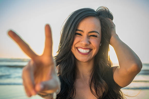 istock Young Hispanic Women On The Beach Peace Sign 636894410
