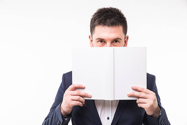 istock Young man in suit cover face with book 636897264