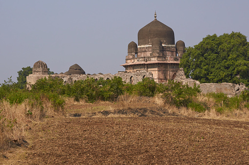 Darya Khan's tomb in the hilltop fortress of Mandu. Building with central dome and a smaller dome on each corner in a walled compound. 16th Century AD