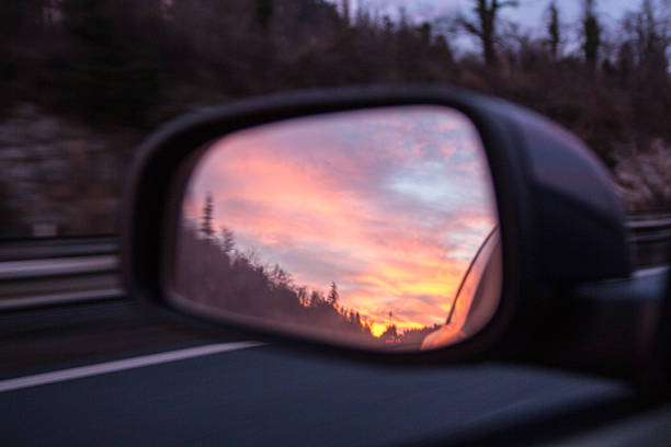 istock Car rear view mirror with sunset and clouds 636899912