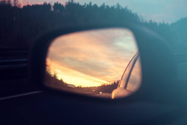 istock Rear view mirror with sunset and clouds 636899924