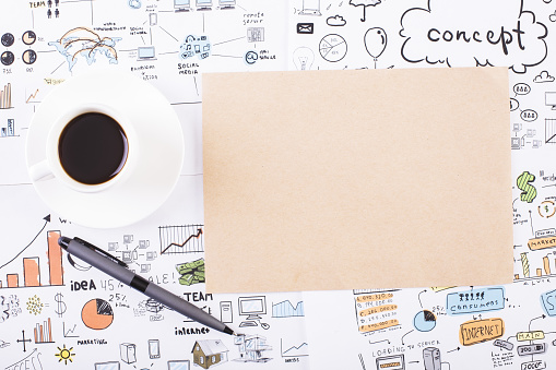 Top view of desktop with blank brown paper, coffee cup, pen and business sketch. Mock up