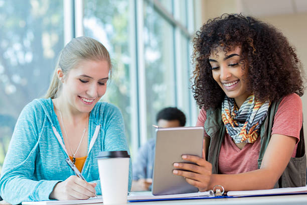istock Diverse female college students work on project together 636908442
