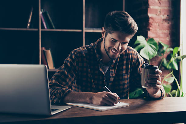 istock Portrait of young happy manager making notes and drinking coffee 636908970