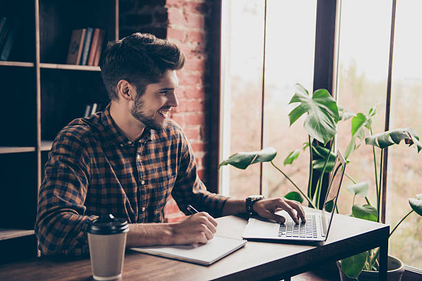 istock Smiling businessman working with laptop and making notes 636908992
