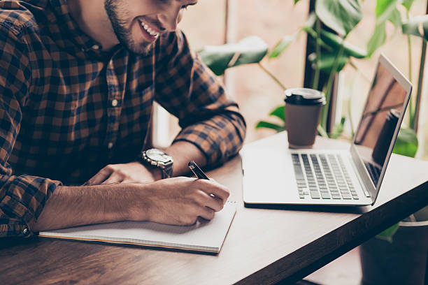 istock Close up of young happy man writing in his notebook 636909014