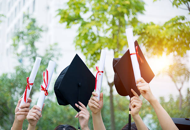 istock Graduates holding motarboards and diplomas 636910064